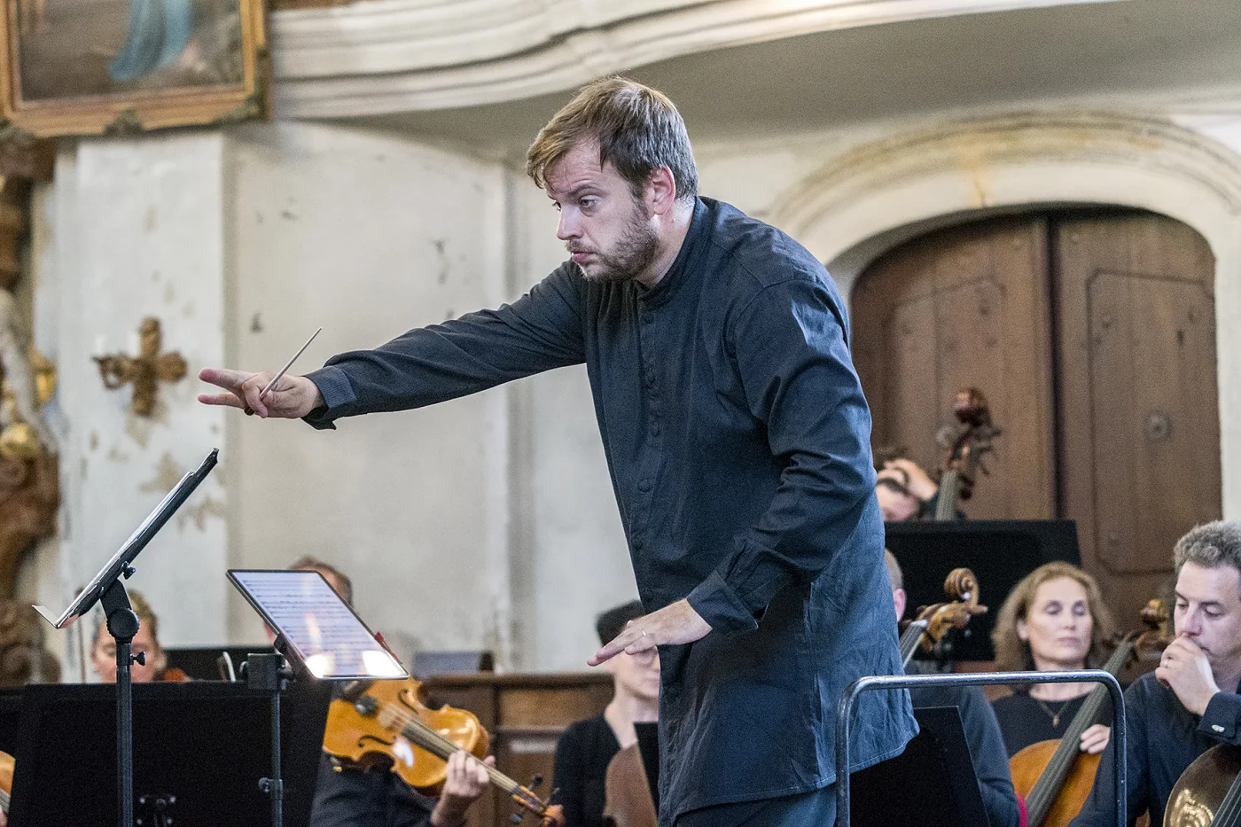 Jiří Kabát conducting a chamber orchestra in a church