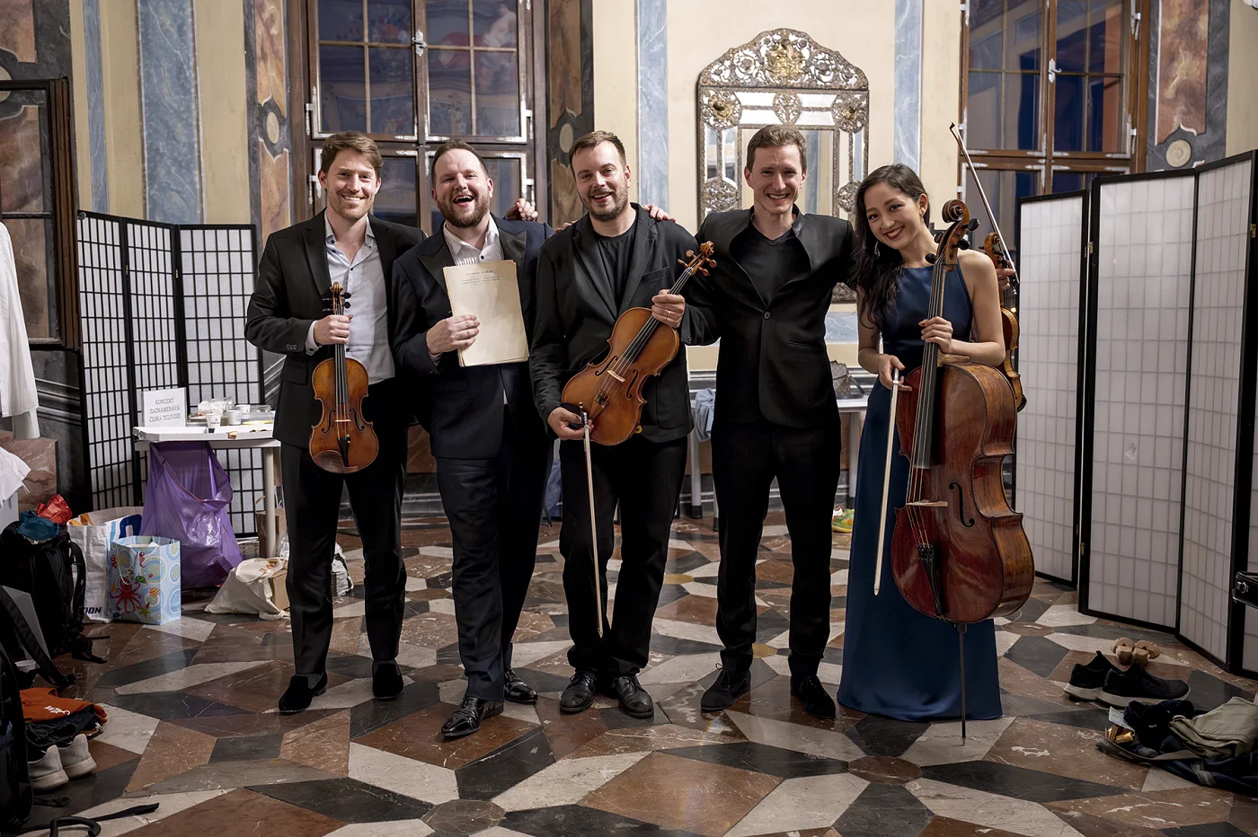 Five musicians with their instruments in a chateau hall