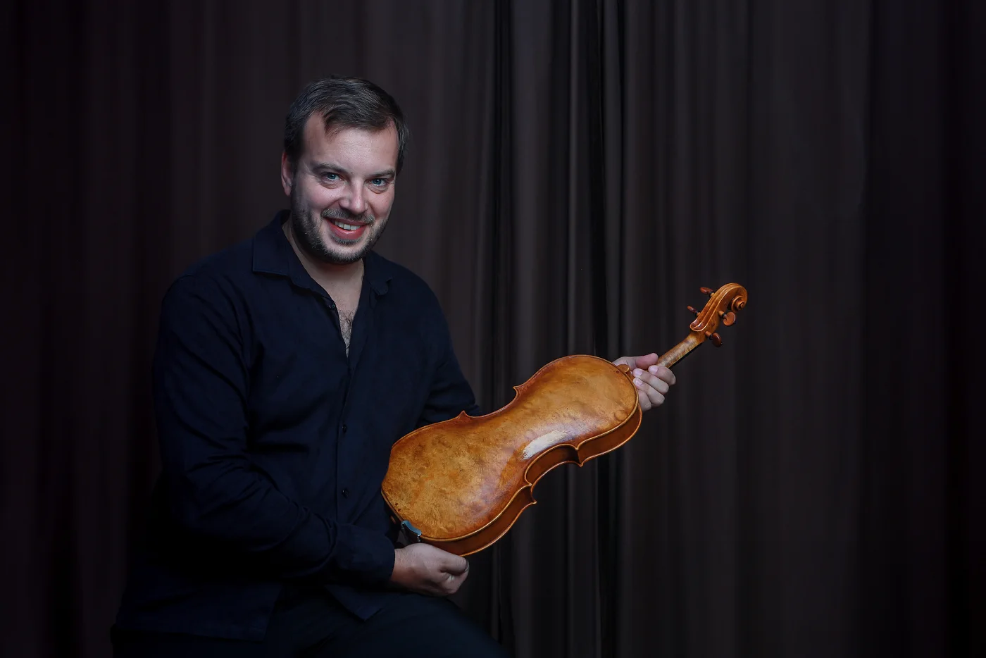 Jiří Kabát seated, holding his viola with its back facing the camera
