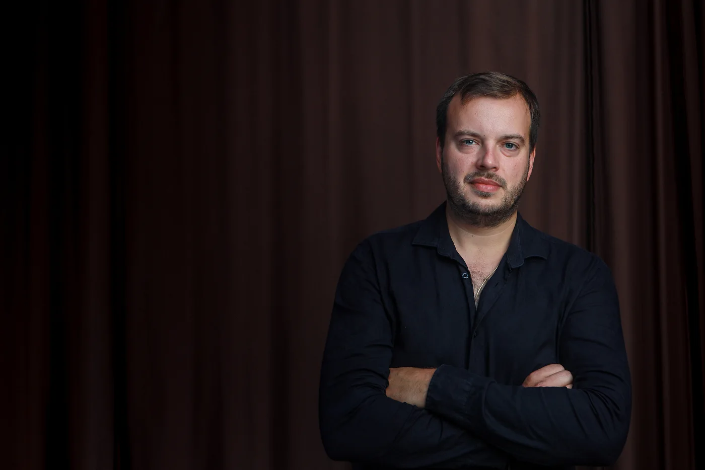 Jiří Kabát with arms crossed in front of a brown curtain
