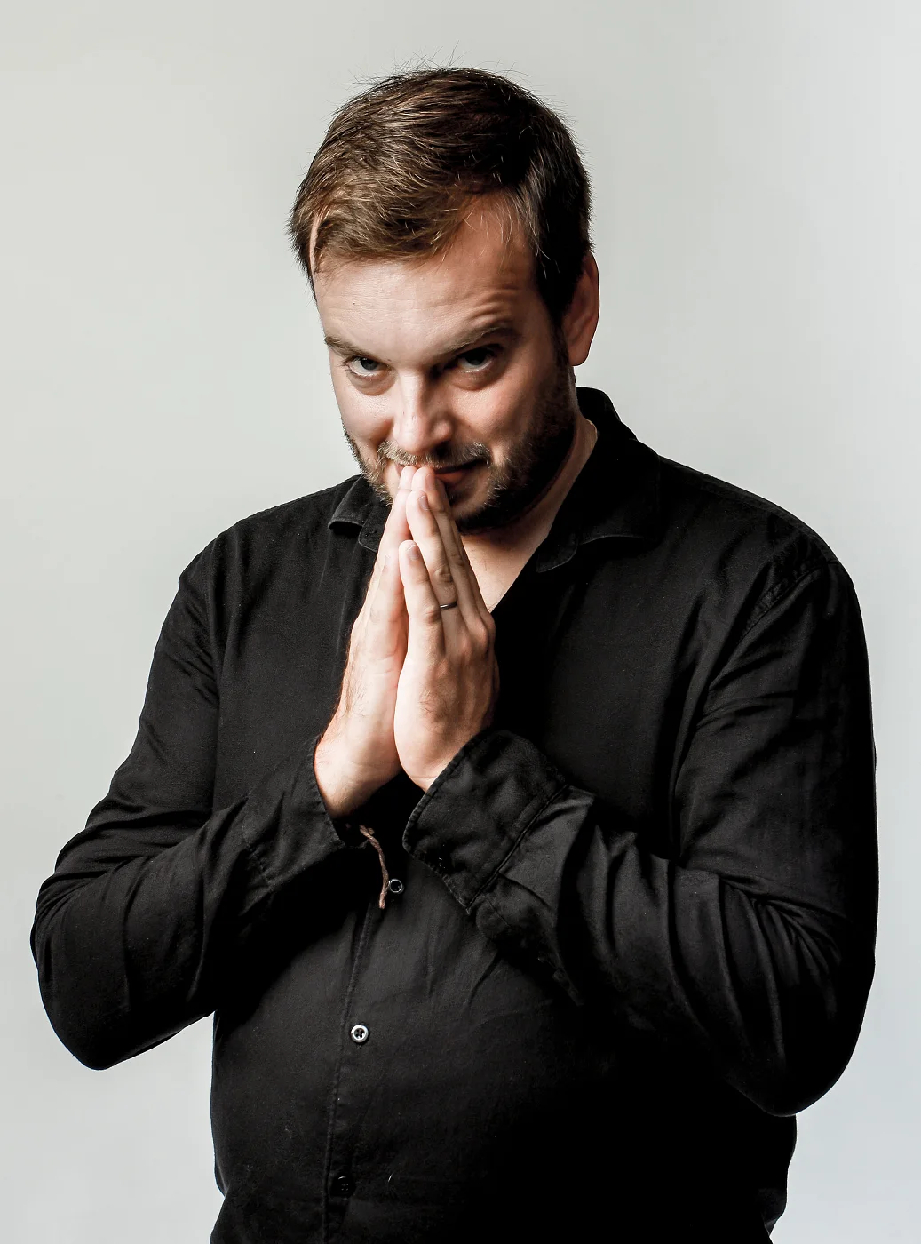 Jiří Kabát with hands pressed together and a mischievous smile